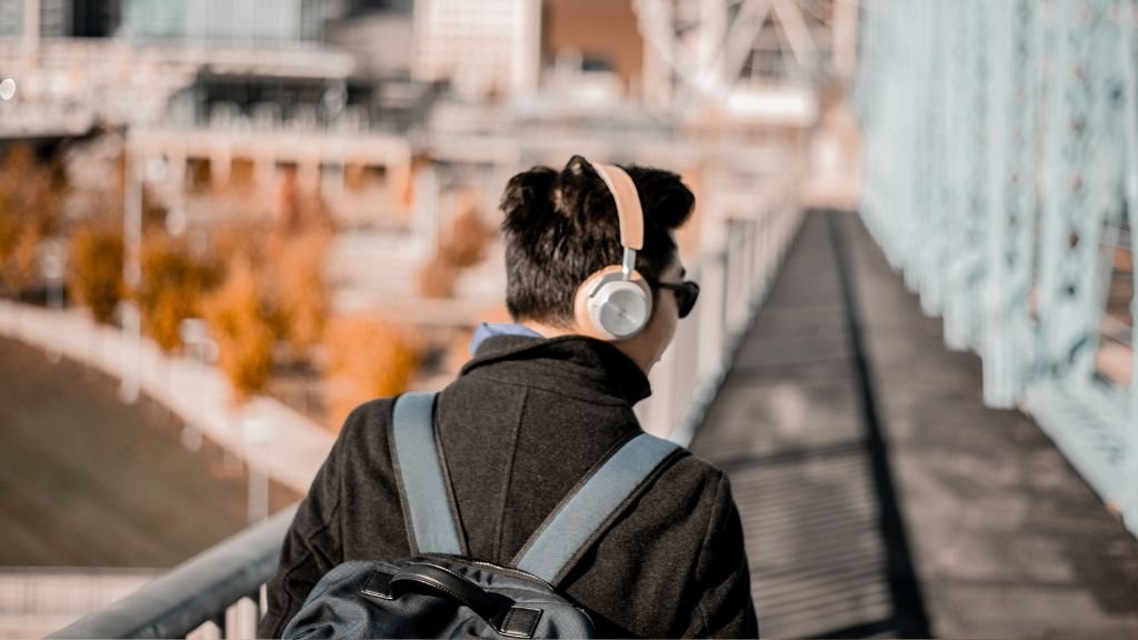 Man wearing headphones and a backpack walking outside